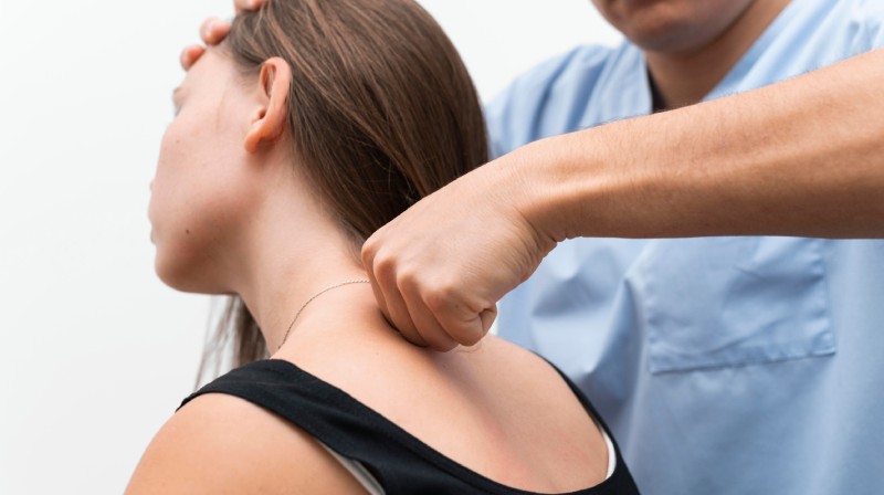Terapeuta evaluando la musculatura cervical de un paciente con dolor de cabeza de origen muscular.